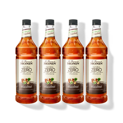 Four 1L plastic bottles of Monin Natural Zero Hazelnut syrup in a row