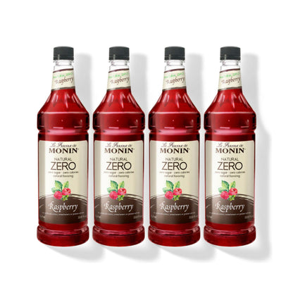 Four 1L plastic bottles of Monin Natural Zero Raspberry syrup in a row